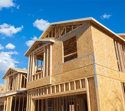 Home being constructed under a bright blue sky