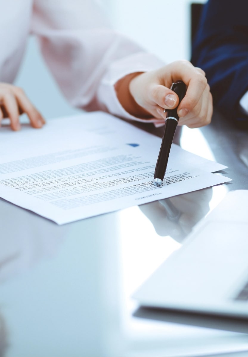 A woman pointing a pen at a stack of paper