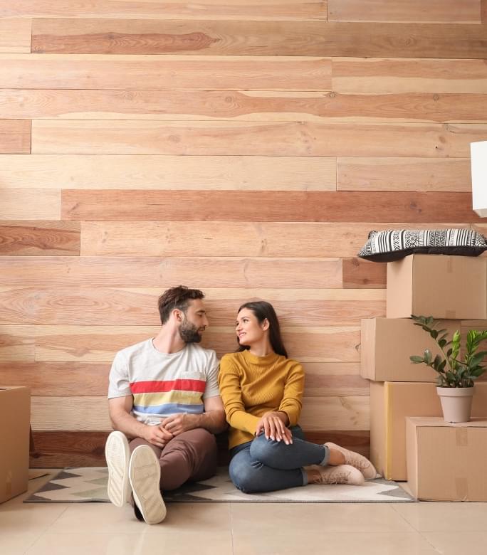 Happy couple sitting on floor next to moving boxes