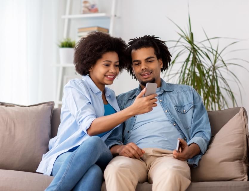 Couple sitting on couch viewing something on a phone