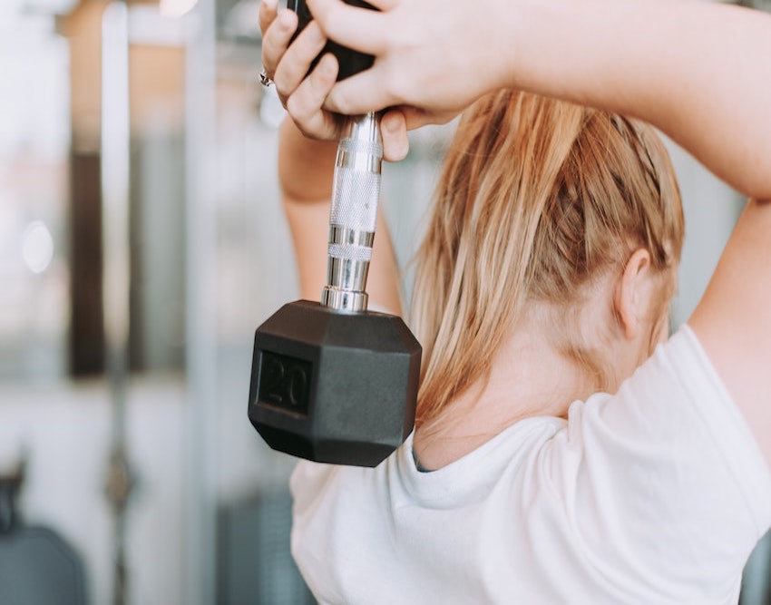 girl holding weight behind her hair