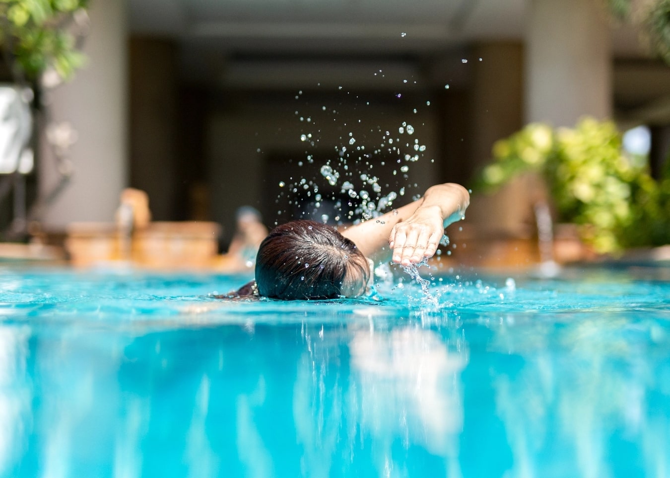 A woman swimming freestyle in her pool