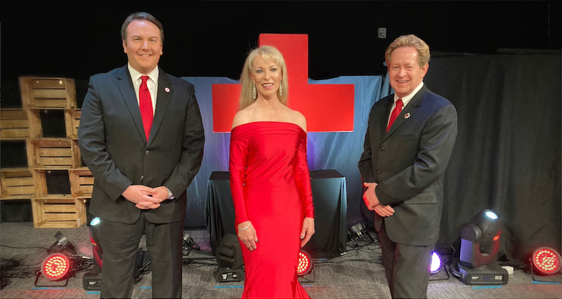 Linda in a red dress in front of Red Cross logo